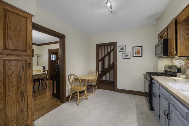 516 Clinton Ave, Oak Park, IL 60304 - kitchen featuring gas stove, light countertops, rail lighting, and brown cabinetry