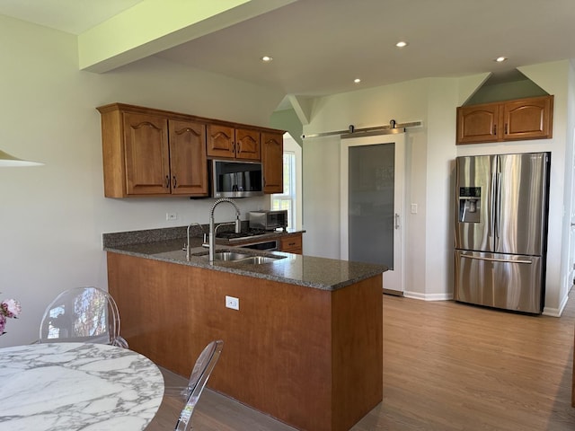 2303 Kentuck Ct, Naperville, IL 60564 - kitchen featuring appliances with stainless steel finishes, a sink, a peninsula, a barn door, and light wood finished floors