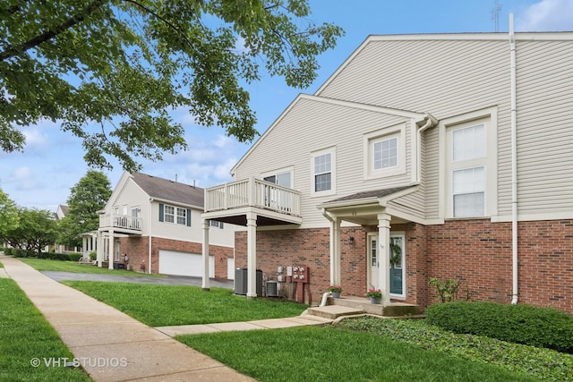 66 N Palazzo Dr, Addison, IL 60101 - view of front facade with a balcony, brick siding, a front yard, and central AC unit