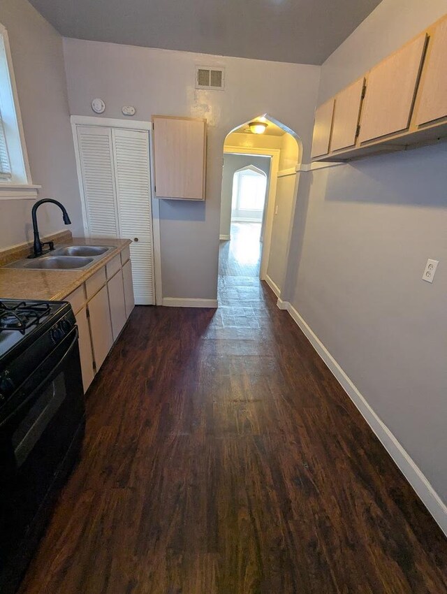 7545 S May St, Chicago, IL 60620 - kitchen with a sink, gas stove, dark wood-type flooring, arched walkways, and baseboards