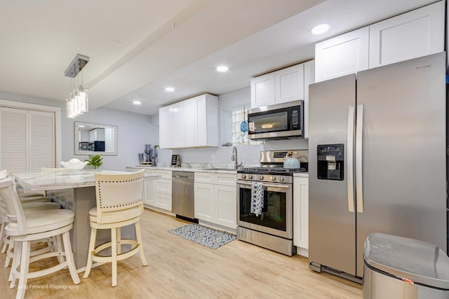 8027 S Green St, Chicago, IL 60620 - kitchen featuring appliances with stainless steel finishes, white cabinets, a kitchen bar, light wood-style floors, and a sink