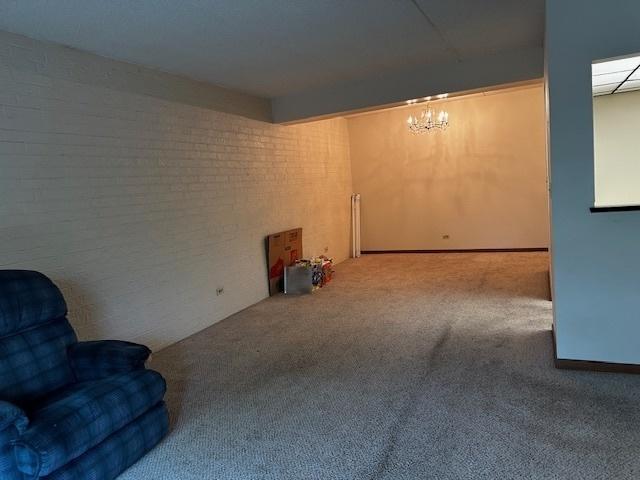 1423 Woodbridge Rd Unit 1F, Joliet, IL 60436 - unfurnished room with carpet, brick wall, and a chandelier