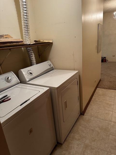 1423 Woodbridge Rd Unit 1F, Joliet, IL 60436 - laundry area featuring washing machine and dryer, light tile patterned flooring, and light colored carpet