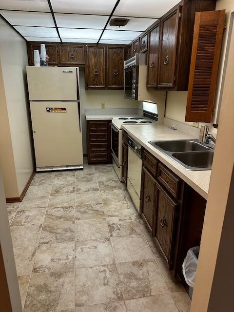 1423 Woodbridge Rd Unit 1F, Joliet, IL 60436 - kitchen featuring white appliances, a sink, dark brown cabinets, light countertops, and stone finish floors