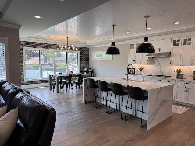 35 E Woodworth Pl, Roselle, IL 60172 - kitchen with a sink, open floor plan, a chandelier, under cabinet range hood, and stainless steel gas stovetop