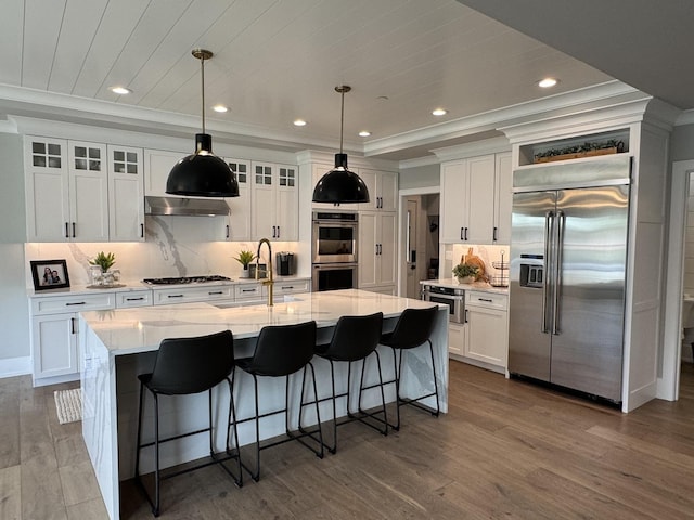 35 E Woodworth Pl, Roselle, IL 60172 - kitchen featuring stainless steel appliances, white cabinetry, decorative backsplash, a center island with sink, and a breakfast bar area
