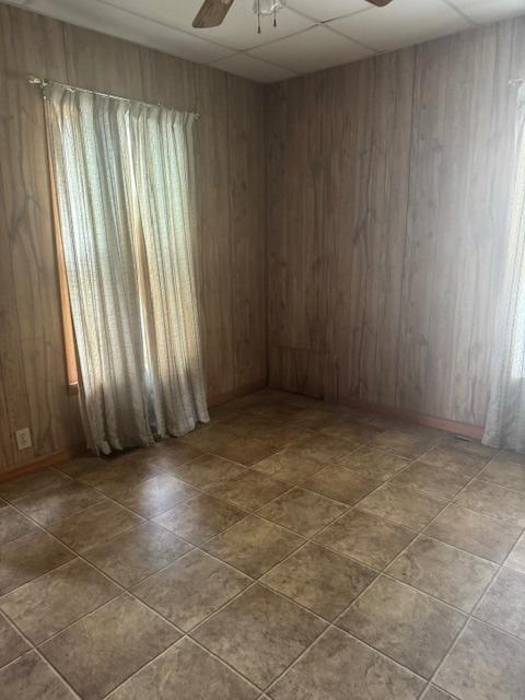 303 W Prairie St, Pontiac, IL 61764 - unfurnished room featuring a ceiling fan, wooden walls, and a paneled ceiling