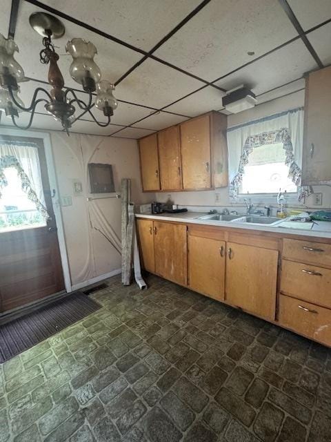 303 W Prairie St, Pontiac, IL 61764 - kitchen featuring a sink, light countertops, a paneled ceiling, a chandelier, and brown cabinetry
