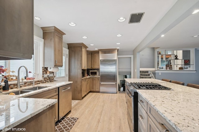 4253 Grove St, Skokie, IL 60076 - kitchen with appliances with stainless steel finishes, a sink, light stone countertops, backsplash, and recessed lighting