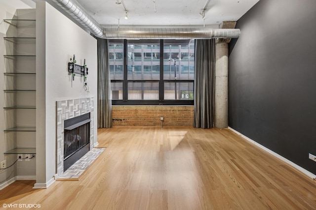 130 S Canal St Unit 216, Chicago, IL 60606 - unfurnished living room featuring track lighting, wood finished floors, a tile fireplace, and baseboards