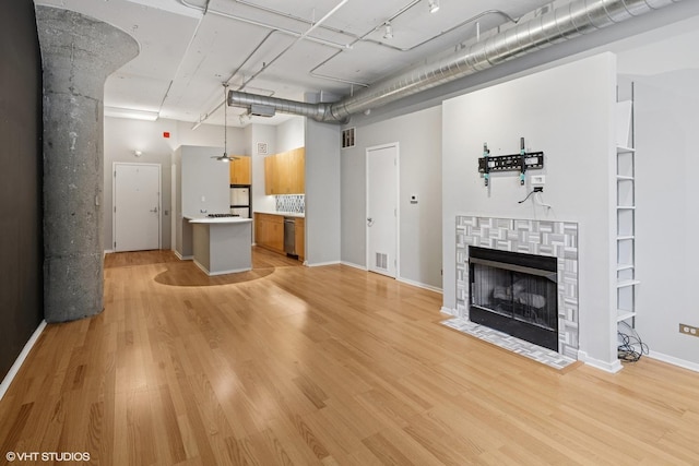 130 S Canal St Unit 216, Chicago, IL 60606 - unfurnished living room featuring light wood-style floors, a towering ceiling, a tile fireplace, and baseboards