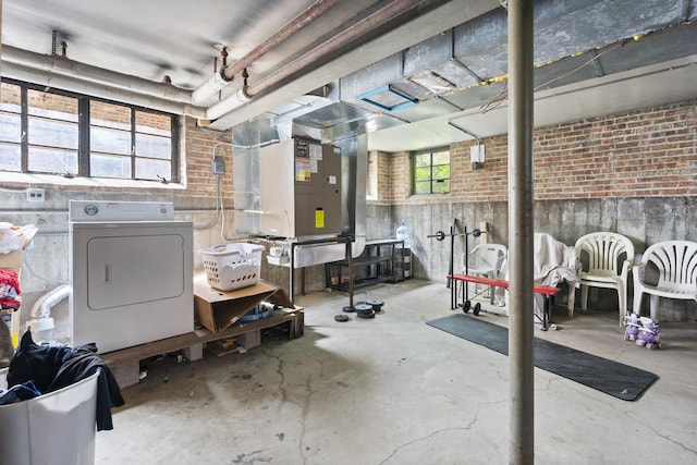 basement featuring washer / clothes dryer, heating unit, and brick wall