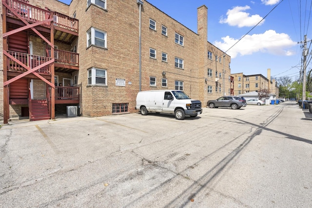 view of property with uncovered parking, central air condition unit, and stairs