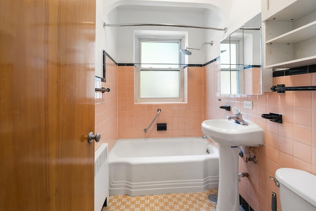full bath featuring tile walls, toilet, radiator, bathtub / shower combination, and tile patterned floors