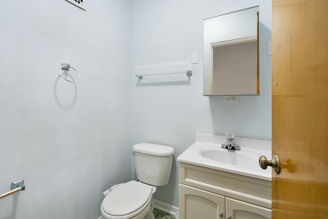 bathroom featuring toilet, vanity, and baseboards