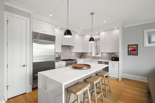 736 W Melrose St Unit 4W, Chicago, IL 60657 - kitchen with high quality appliances, a sink, tasteful backsplash, a kitchen bar, and white cabinetry