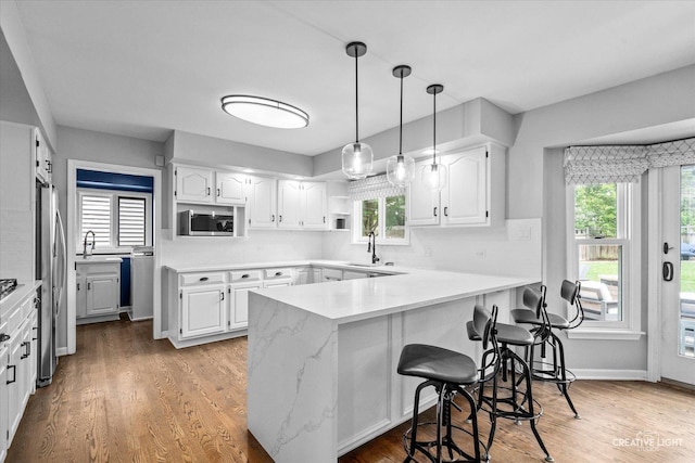 2255 University Dr, Naperville, IL 60565 - kitchen featuring appliances with stainless steel finishes, a peninsula, white cabinetry, and light wood-style flooring