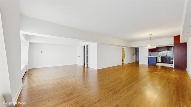 175 E Delaware Pl Unit 6401, Chicago, IL 60611 - unfurnished living room featuring a chandelier, light wood-style floors, and baseboards