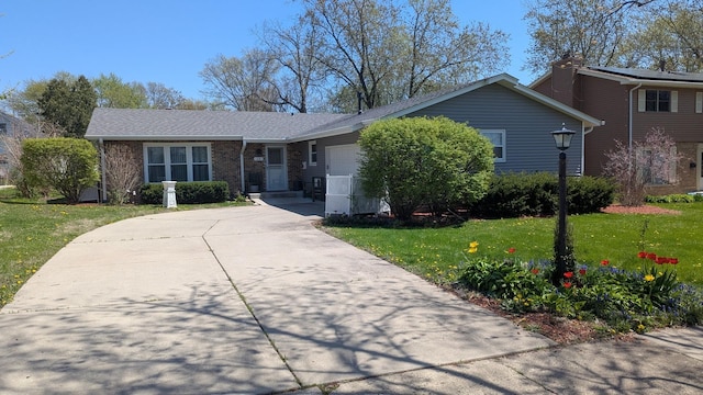 view of front of home with an attached garage, a front lawn, concrete driveway, and brick siding