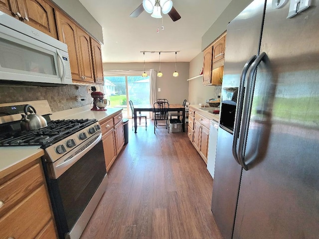 kitchen featuring appliances with stainless steel finishes, dark wood finished floors, a ceiling fan, light countertops, and brown cabinetry