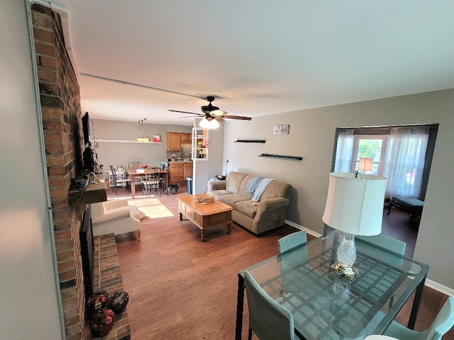 living room with wood finished floors, a ceiling fan, and baseboards