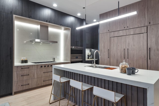 2049 W Race Ave, Chicago, IL 60612 - kitchen with stainless steel double oven, a kitchen bar, gas stovetop, a sink, and wall chimney range hood