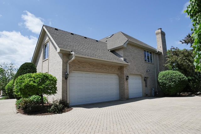5 Todor Ct, Burr Ridge, IL 60527 - view of side of property with brick siding, a chimney, decorative driveway, roof with shingles, and a garage