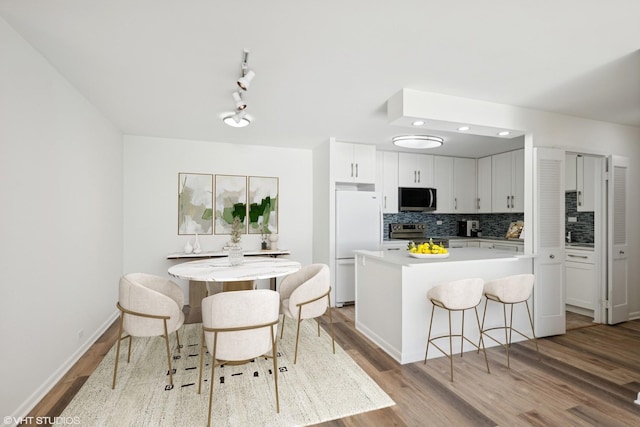 155 N Harbor Dr Unit 610, Chicago, IL 60601 - kitchen featuring stainless steel appliances, a center island, a kitchen breakfast bar, wood finished floors, and tasteful backsplash