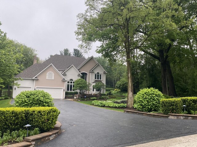 1312 Galloway Dr, Woodstock, IL 60098 - view of front facade with driveway, stucco siding, a chimney, and roof with shingles