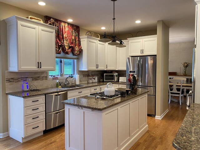 1312 Galloway Dr, Woodstock, IL 60098 - kitchen with stainless steel appliances, a sink, white cabinetry, tasteful backsplash, and light wood-type flooring