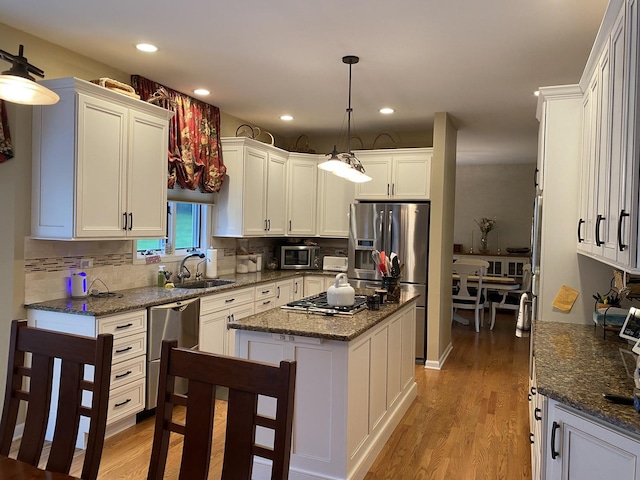 1312 Galloway Dr, Woodstock, IL 60098 - kitchen with a sink, appliances with stainless steel finishes, backsplash, light wood-type flooring, and white cabinetry