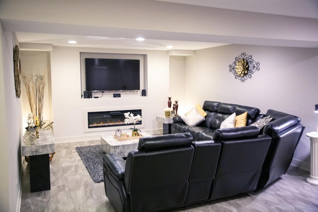 living area with recessed lighting, a glass covered fireplace, and baseboards