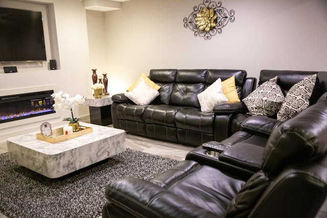 living room featuring a glass covered fireplace and baseboards