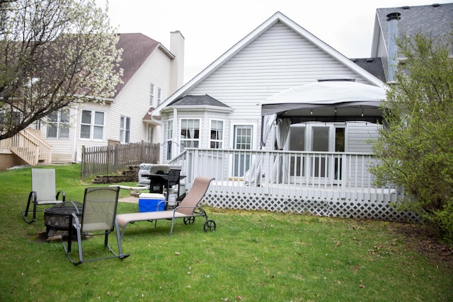 back of house with a gazebo, a fire pit, a deck, and a lawn