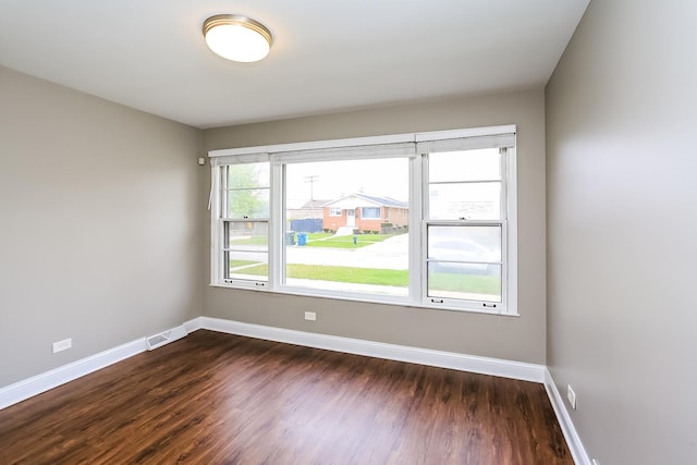 spare room featuring dark wood-type flooring and baseboards