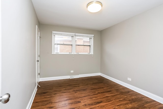 unfurnished room with dark wood-type flooring and baseboards