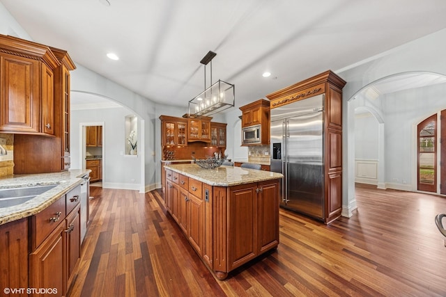 210 S Prospect St, Clarendon Hills, IL 60514 - kitchen featuring built in appliances, arched walkways, dark wood-type flooring, baseboards, and tasteful backsplash