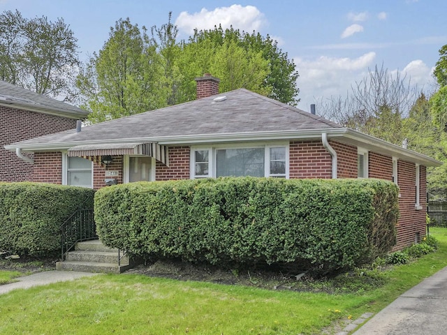 341 W Glen Flora Ave, Waukegan, IL 60085 - view of front of property with brick siding, a chimney, a front yard, and a shingled roof