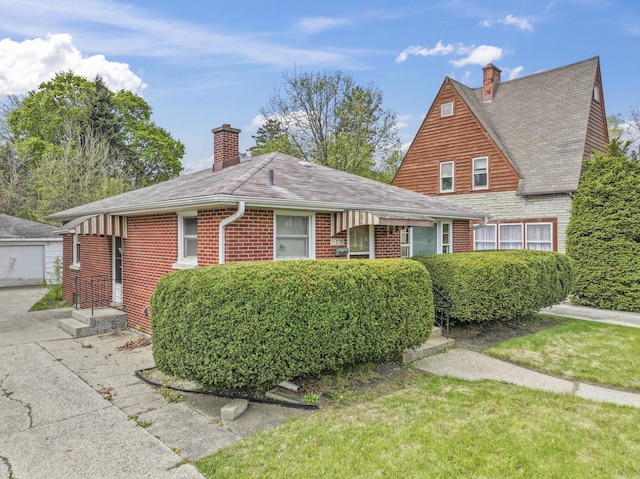 341 W Glen Flora Ave, Waukegan, IL 60085 - view of front of house featuring a chimney, an outbuilding, roof with shingles, brick siding, and a front lawn
