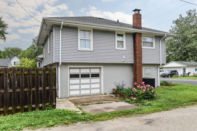 1502 S Mill St, Pontiac, IL 61764 - view of front facade with a chimney, an attached garage, central AC, and a shingled roof