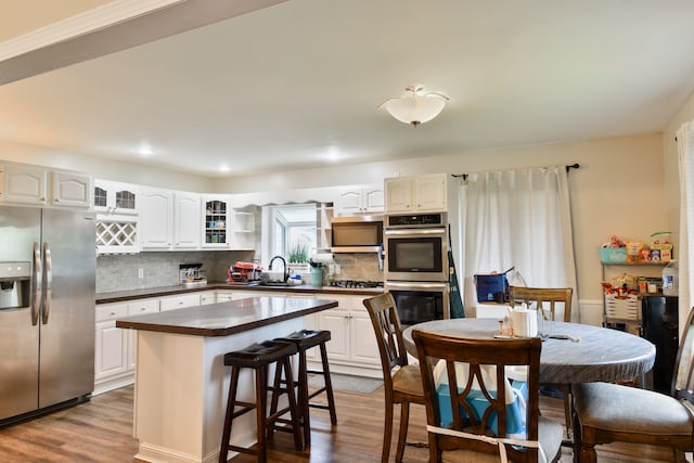 1502 S Mill St, Pontiac, IL 61764 - kitchen featuring appliances with stainless steel finishes, dark countertops, dark wood-type flooring, decorative backsplash, and white cabinetry