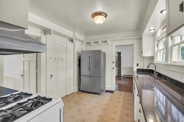 402 S Coler Ave, Urbana, IL 61801 - kitchen featuring freestanding refrigerator, gas range gas stove, exhaust hood, white cabinetry, and dark stone countertops
