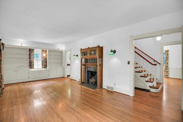 402 S Coler Ave, Urbana, IL 61801 - unfurnished living room featuring a tile fireplace, hardwood / wood-style floors, and stairway