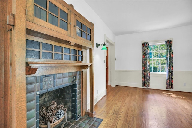 402 S Coler Ave, Urbana, IL 61801 - unfurnished living room featuring wood finished floors, a fireplace with flush hearth, and wainscoting