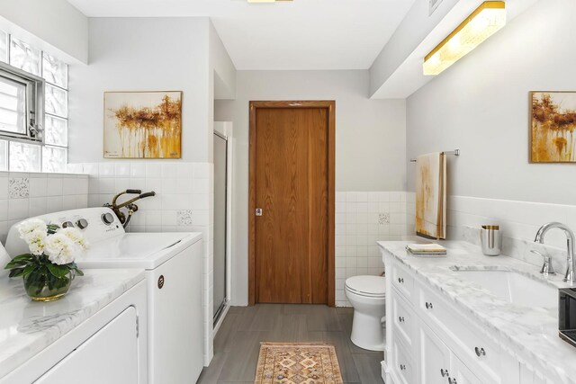 5923 W Giddings St, Chicago, IL 60630 - bathroom featuring tile walls, washing machine and dryer, a shower stall, wood finished floors, and vanity