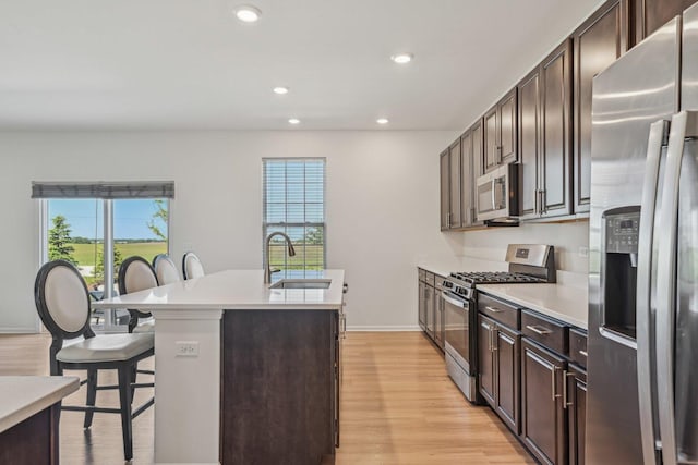 1486 Keller St, Elburn, IL 60119 - kitchen featuring stainless steel appliances, a sink, a breakfast bar area, a kitchen island with sink, and light wood-style floors