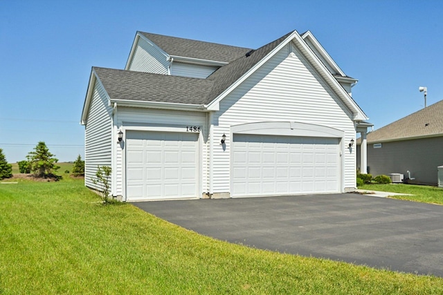 1486 Keller St, Elburn, IL 60119 - traditional home featuring an attached garage, asphalt driveway, a front lawn, roof with shingles, and central air condition unit