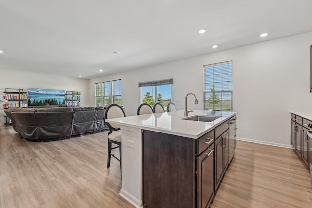 1486 Keller St, Elburn, IL 60119 - kitchen with a sink, a breakfast bar, stainless steel dishwasher, dark brown cabinetry, and light wood-style flooring