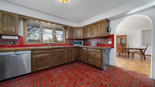 4012 Lisa Dr, Rockford, IL 61114 - kitchen featuring stainless steel appliances, arched walkways, a sink, tasteful backsplash, and dark countertops