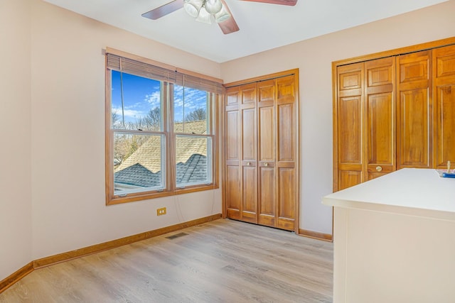 971 Heathrow Ln, Naperville, IL 60540 - unfurnished bedroom featuring light wood-style flooring, baseboards, two closets, and a ceiling fan